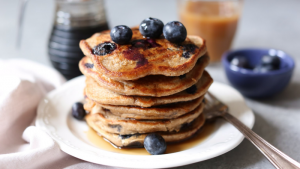 Banaanpannenkoekjes met blauwe bessen op wit bord