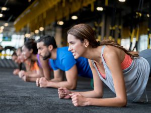 Sporters doen een plankhouding op de grond