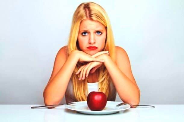 vrouw zit aan tafel met alleen een appel op haar bord