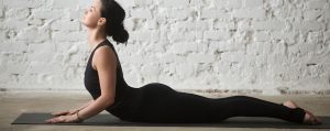 jonge aantrekkelijke vrouw beoefent cobra oefening op yoga matje