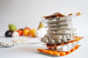 verschillende soorten tabletten op elkaar gestapeld met fruit op de achtergrond
