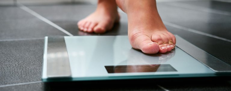 Vrouwelijke blote voeten met weegschaal in de badkamer