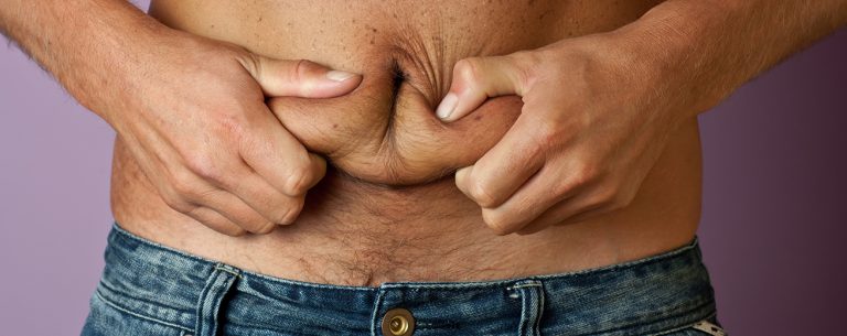 Man houdt zijn buikvet vast met zijn handen op de voorgrond