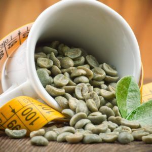Groene koffie bonen extract uit een kopje op houten tafel