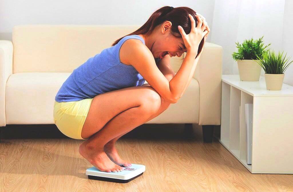 gefrustreerde vrouw staat op de weegschaal en gilt