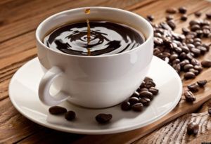 Kopje koffie met koffiebonen op houten tafel