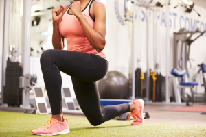 sportende vrouw maakt lunge beweging op een groene mat