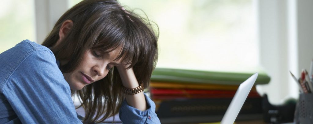 Oververmoeide vrouw zit achter haar bureau