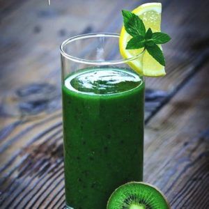 groene smoothie in glas met stuk kiwi ernaast