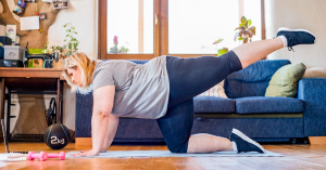 Vrouw doet een sportoefening op een yogamat in de huiskamer